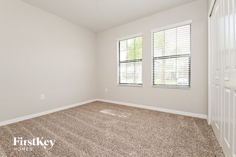 a bedroom with a carpeted floor and two windows