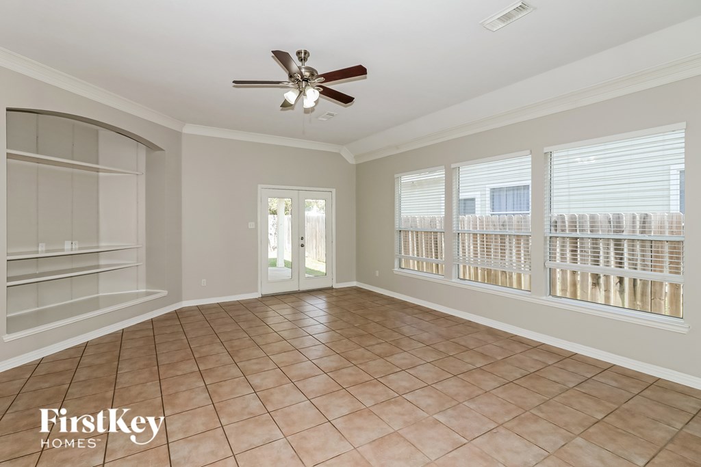 A spacious room with a ceiling fan and sliding glass doors.