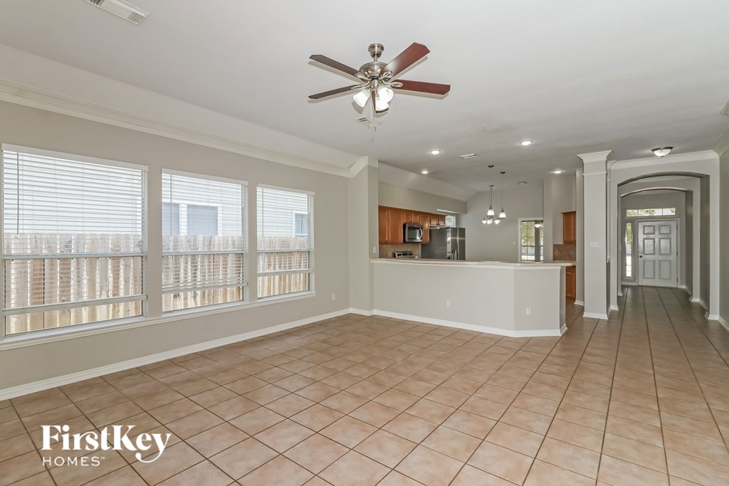 A spacious room with a fan and tiled flooring.