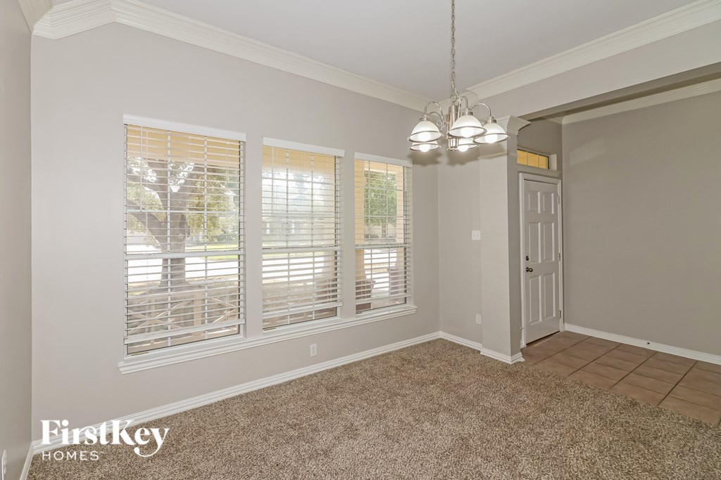 A room with a carpeted floor, a door, and a chandelier.