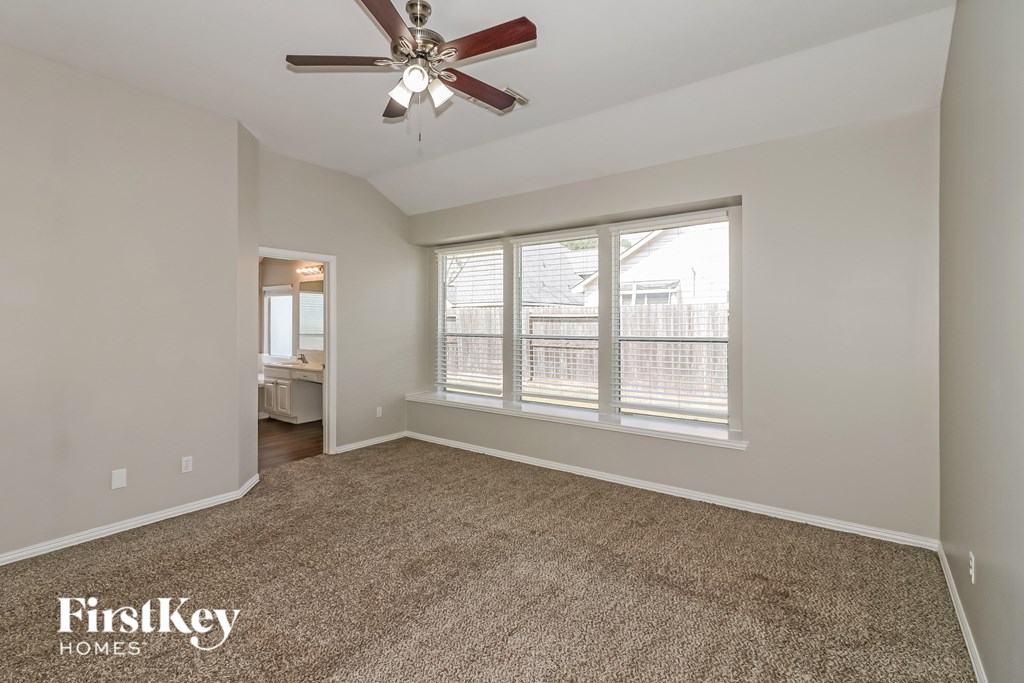 A room with a carpet floor and a ceiling fan.
