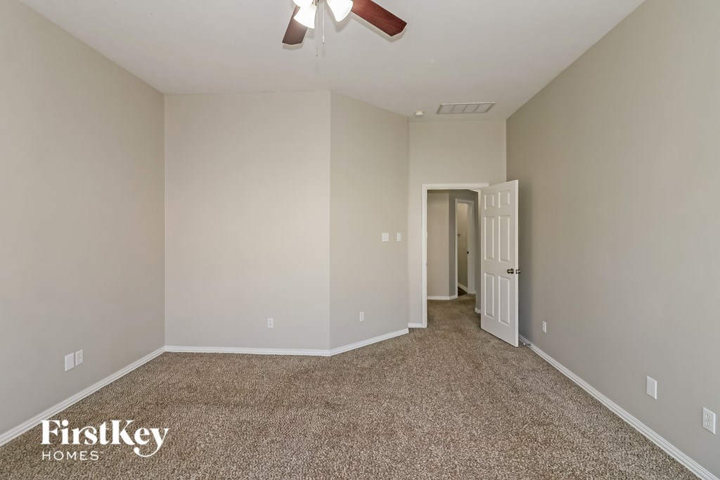 A room with a carpet floor and a ceiling fan.