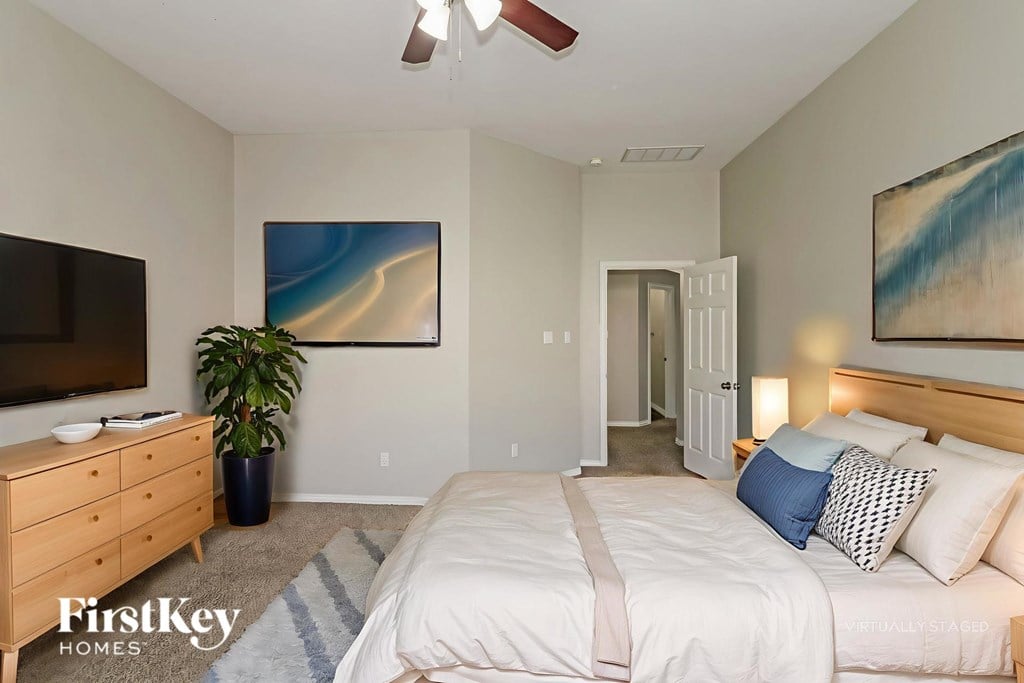 A bedroom with a bed, dresser, and ceiling fan.