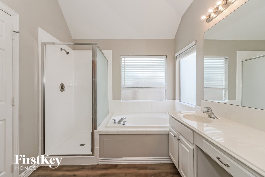 A bathroom with a white tub, sink, and shower.
