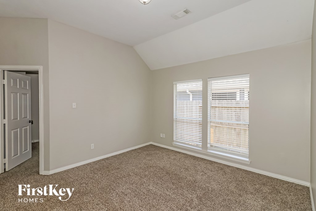 A carpeted room with a door and two windows.
