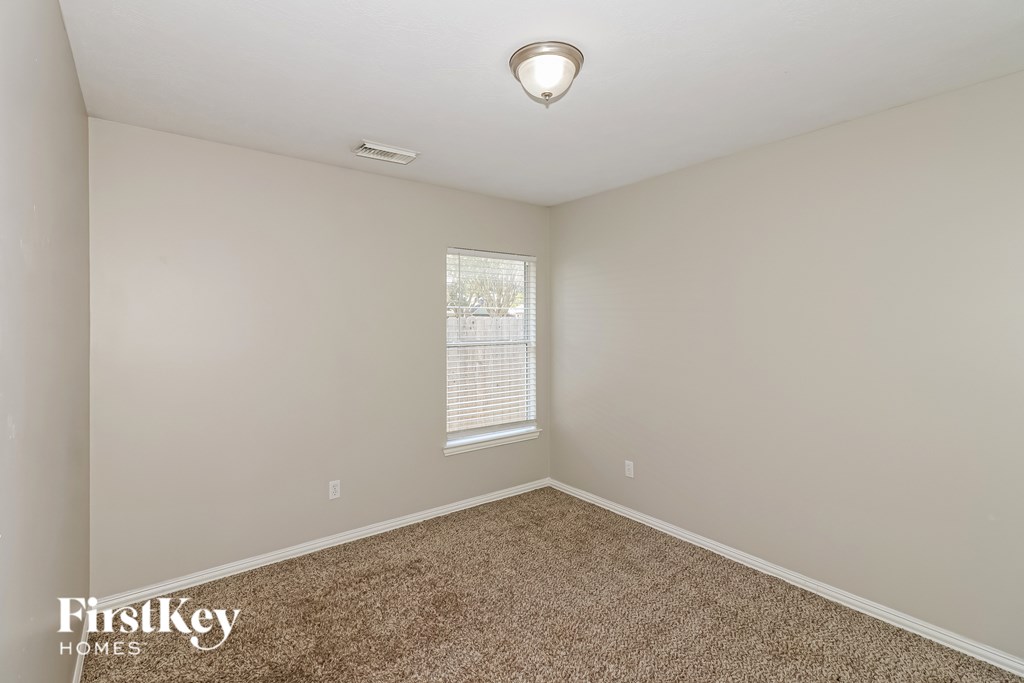 A room with a carpeted floor and a window with blinds.