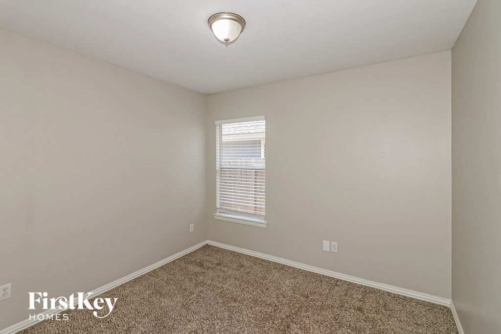 A room with a carpeted floor and a window with blinds.