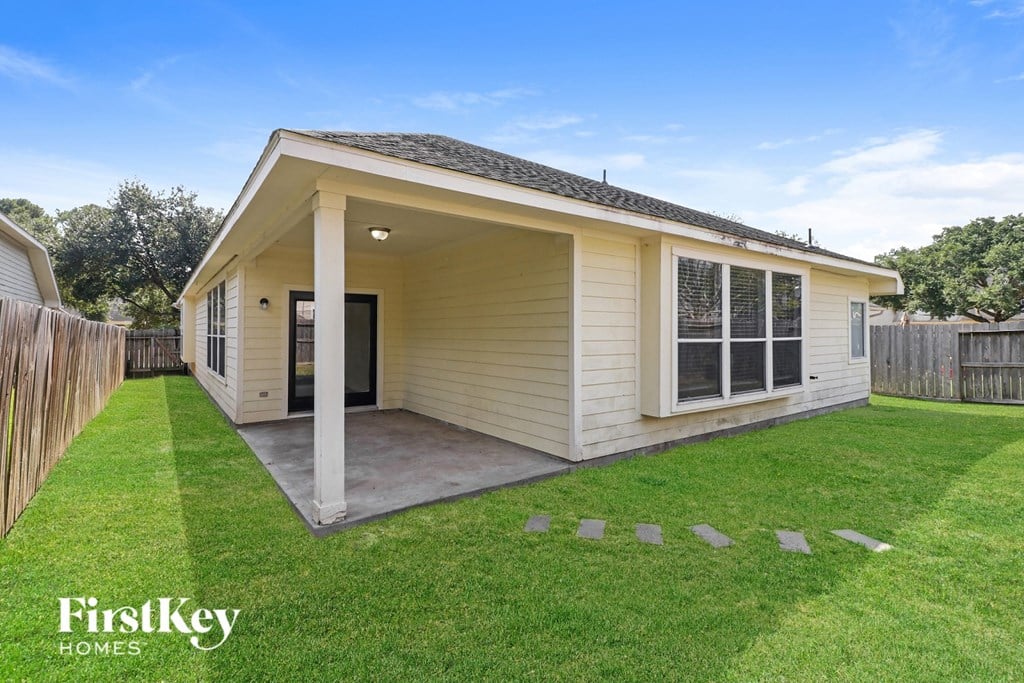 A small house with a porch and a fence in the yard.