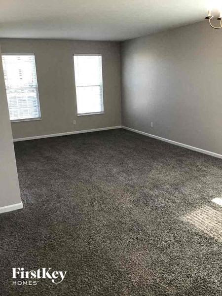 an empty room with a carpeted floor and two windows