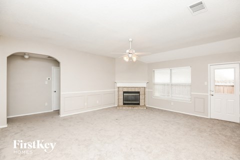 A spacious living room with a fireplace and a chandelier.