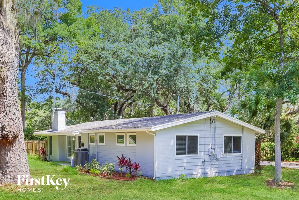 a small white house with a yard and trees