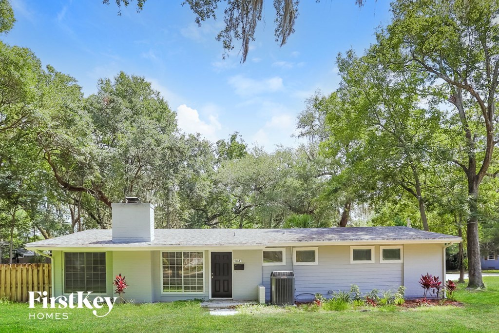 a small white house with trees in the background
