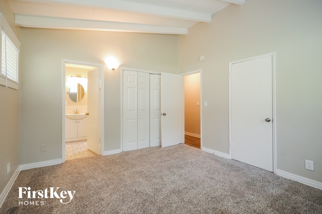 a master bedroom with a carpeted floor and white doors to a bathroom
