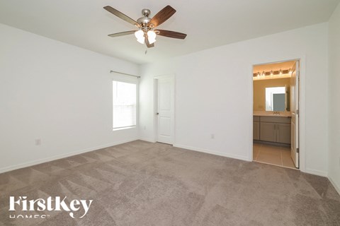 A spacious room with a ceiling fan and a door leading to another room.