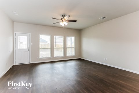 A spacious room with a ceiling fan and sliding glass doors.
