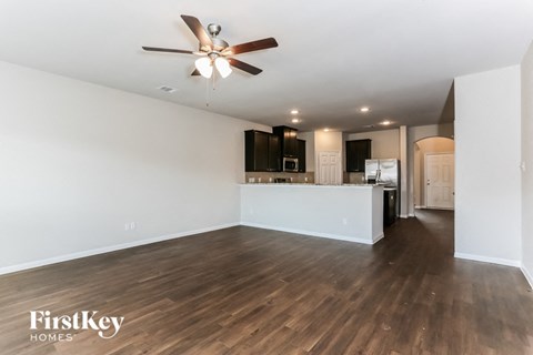 A spacious room with a ceiling fan and wooden flooring.