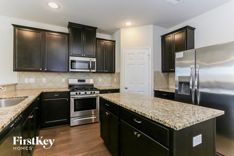 A kitchen with black cabinets and a granite countertop.