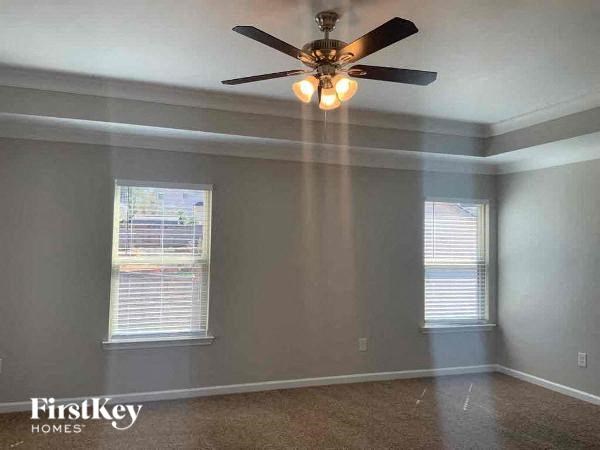 A room with a ceiling fan and two windows.