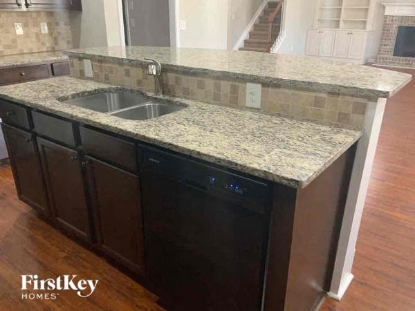 A kitchen with a granite countertop and a black dishwasher.