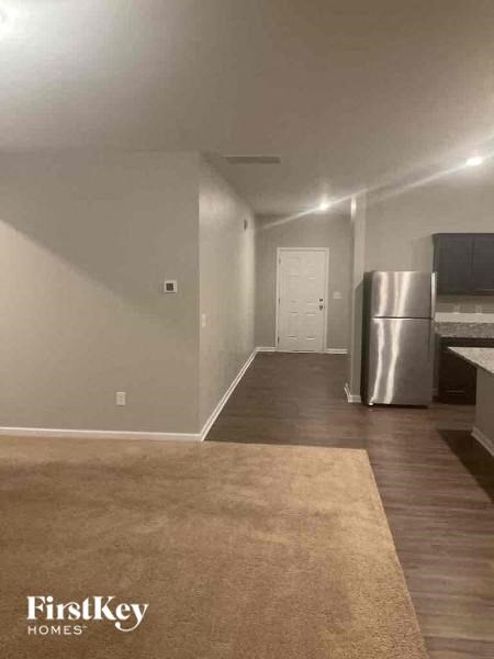 an empty living room with a stainless steel refrigerator