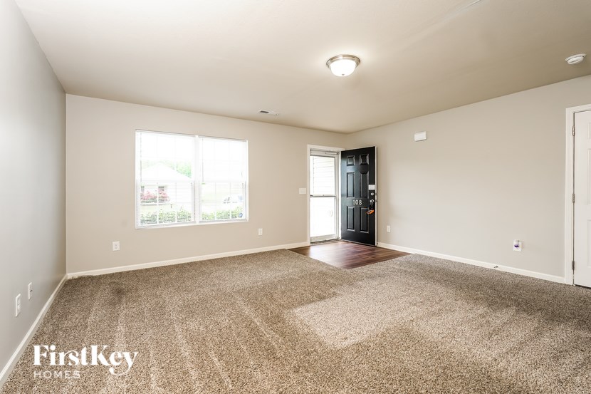 A spacious room with a carpeted floor and a door leading to a balcony.
