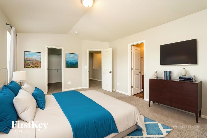 A bedroom with a bed, dresser, and television.
