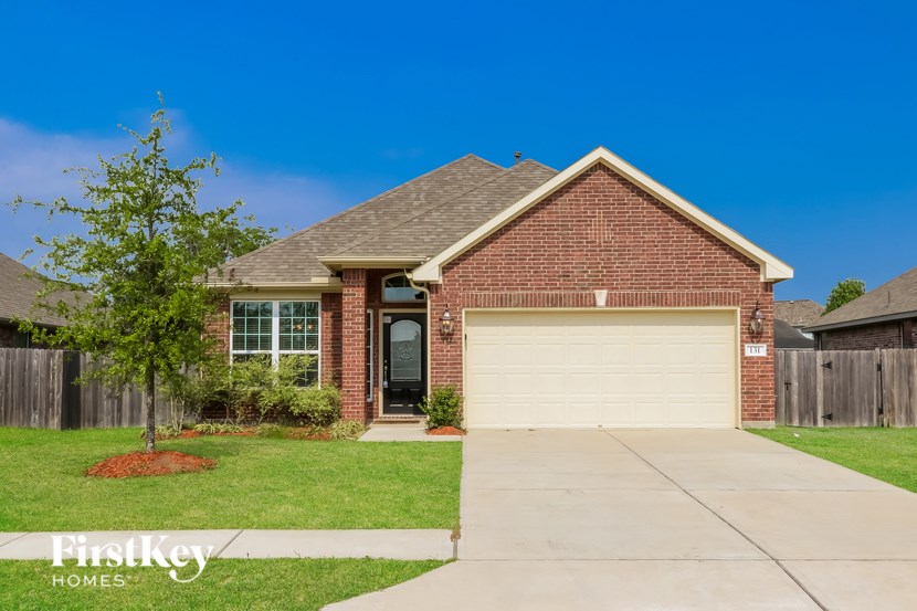 A house with a garage door and a tree in front of it.
