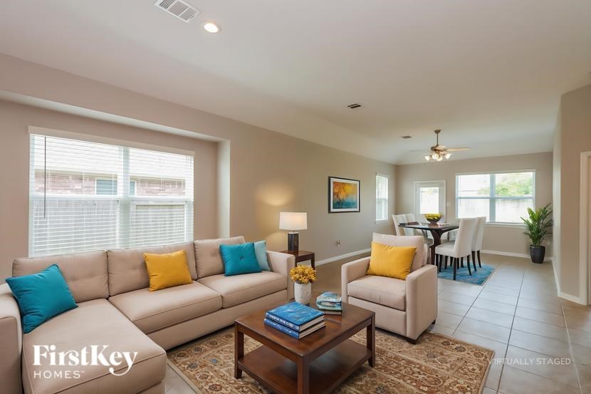 A living room with a beige couch, a coffee table, and a painting on the wall.