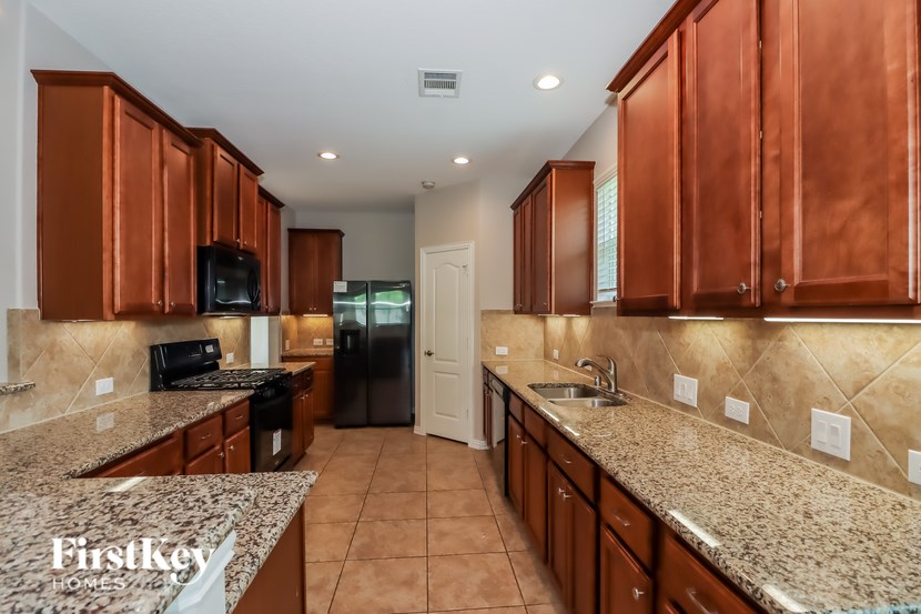 A kitchen with brown cabinets and a granite countertop.