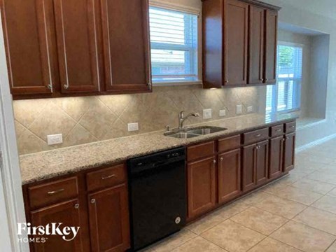 A kitchen with brown cabinets and a black dishwasher.