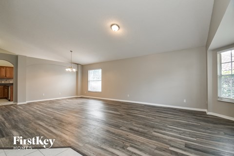 A spacious room with wooden flooring and a large window.