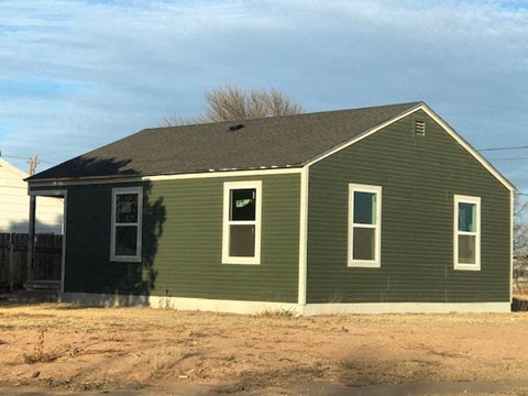 a green house with a dirt field in front of it