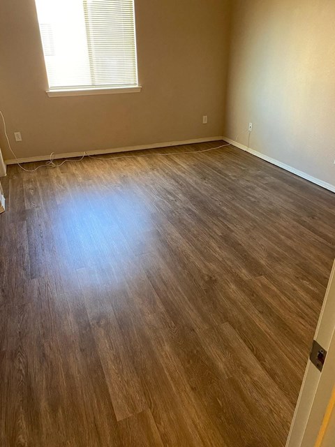 A room with wooden flooring and a window.