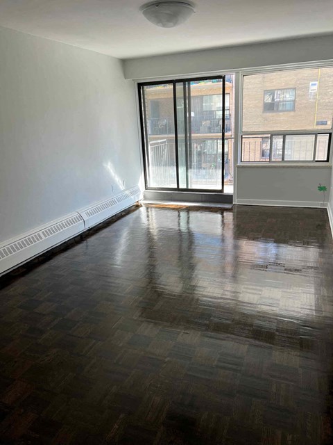 an empty living room with a wood floor and a window