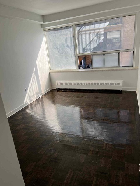 an empty living room with a window and wood floors