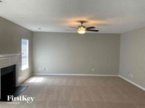 an empty living room with a ceiling fan and a fireplace