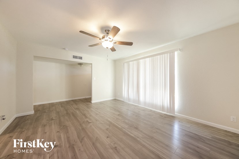a spacious living room with hardwood flooring and a ceiling fan