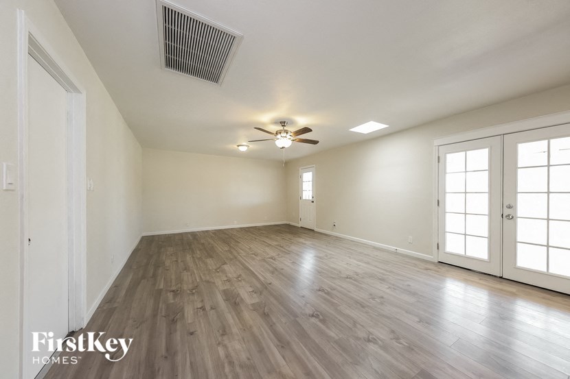 an empty living room with wood flooring and a ceiling fan