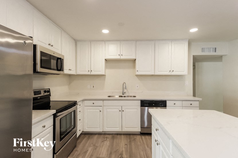 a white kitchen with stainless steel appliances and white cabinets