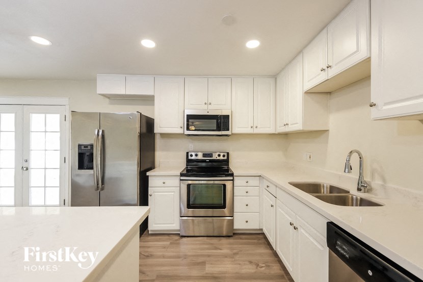 a white kitchen with stainless steel appliances and white cabinets
