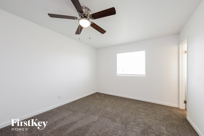 a living room with a ceiling fan and a carpet
