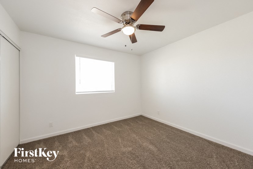 an empty room with a ceiling fan and a window