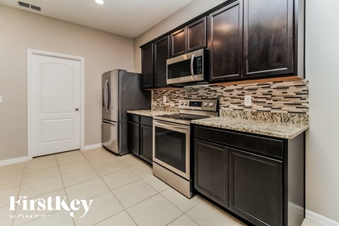 A kitchen with black cabinets and a granite countertop.