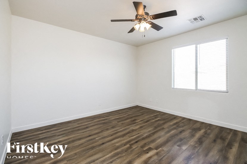 A room with a ceiling fan and wooden flooring.