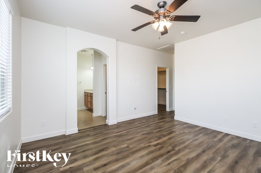 A spacious room with a ceiling fan and wooden flooring.