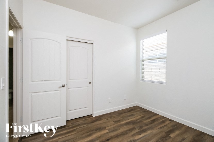 A room with two doors and a window with blinds.