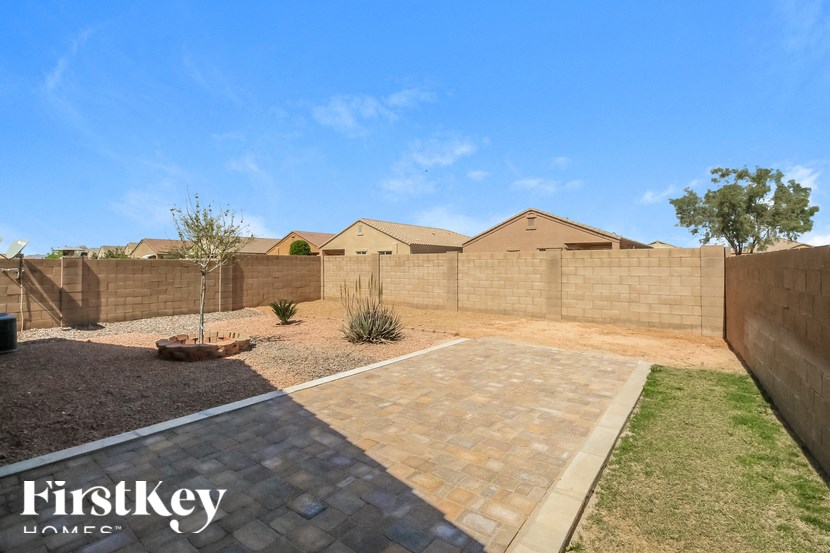 A backyard with a brick patio and a tree.