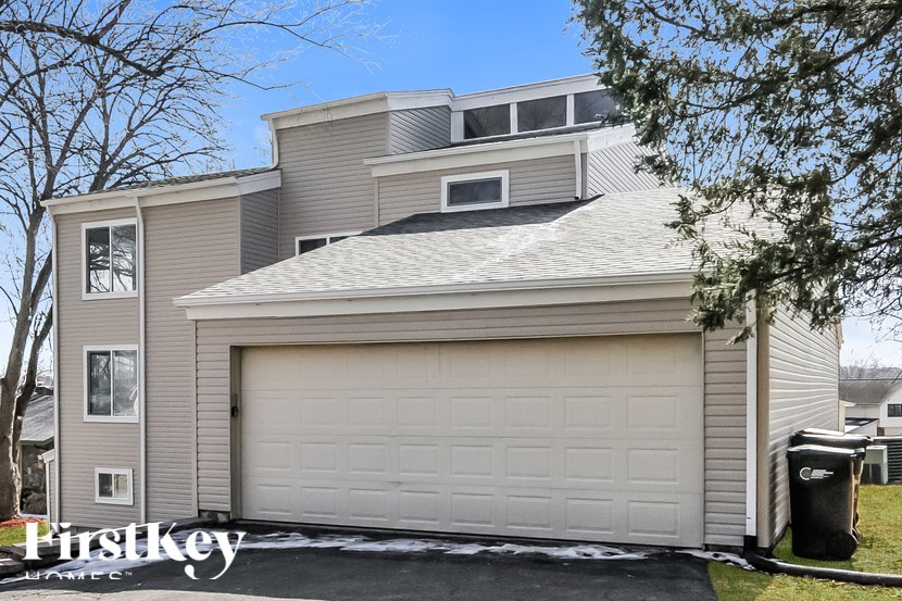 A house with a large garage door and a tree in front.
