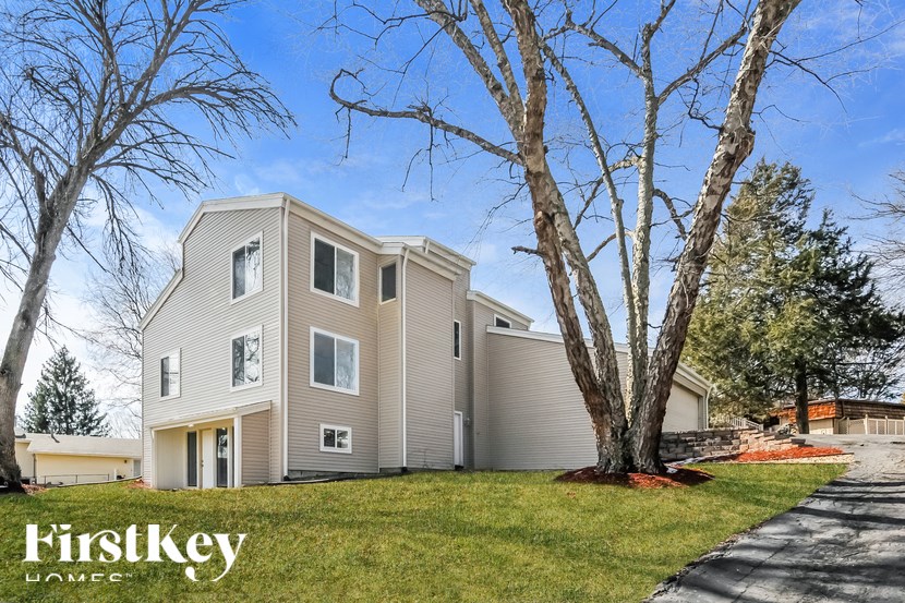 A modern house with a grey exterior and a large tree in front.