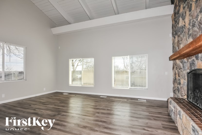 A spacious room with wooden flooring and a stone fireplace.